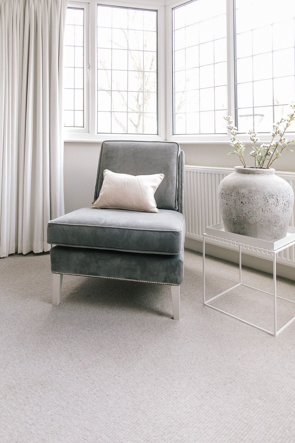 Grey velvet armchair and pastel pink cushion