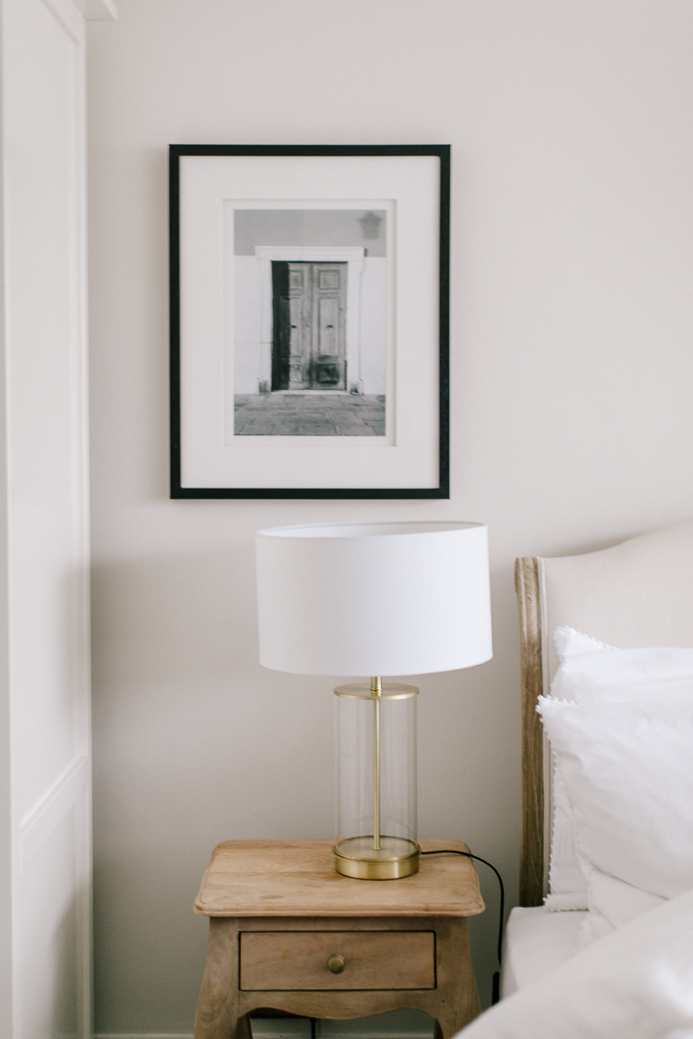 Gold and glass pillar lamp and monochrome art print on bedside table
