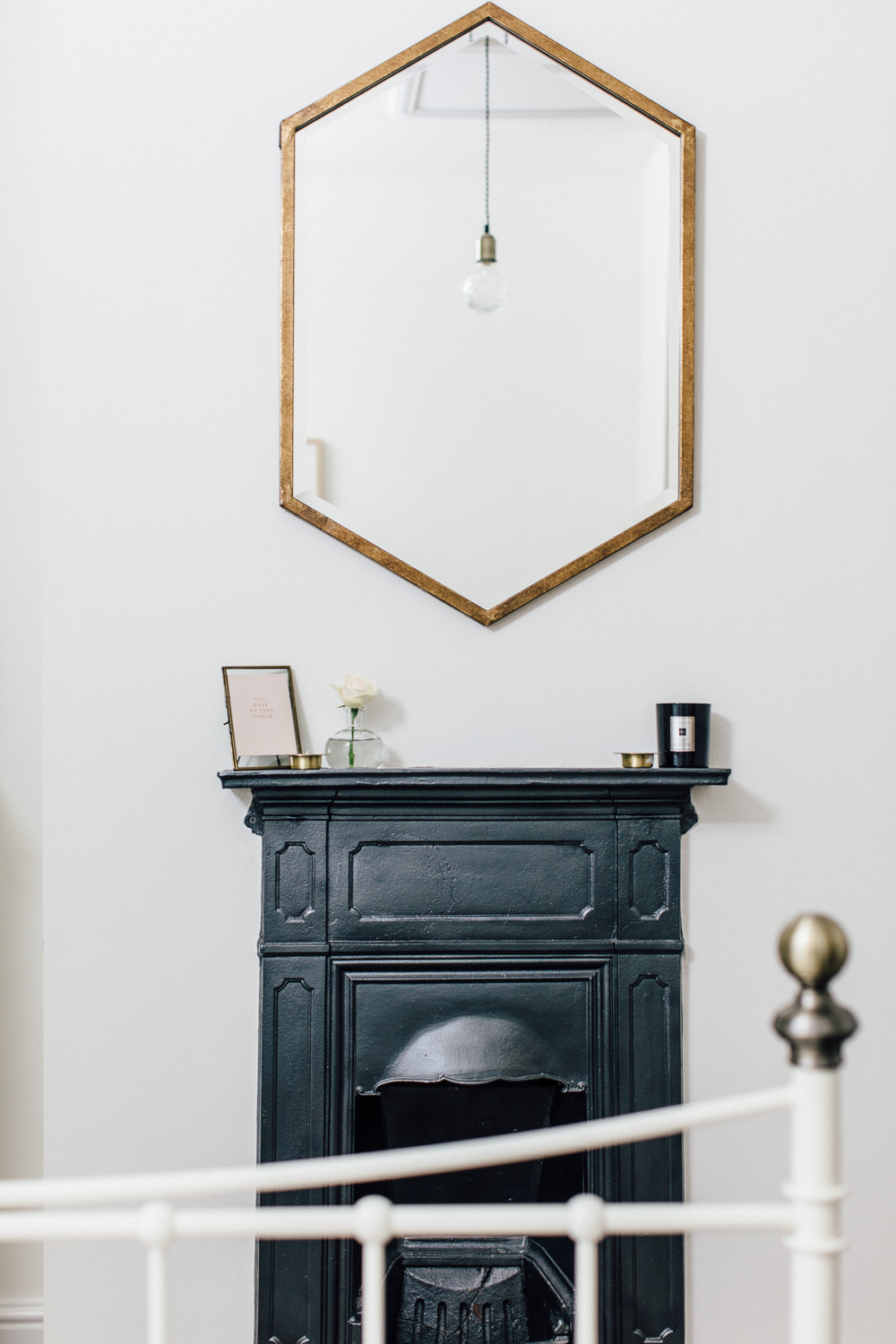 HomeSense hexagonal brass mirror over black fireplace
