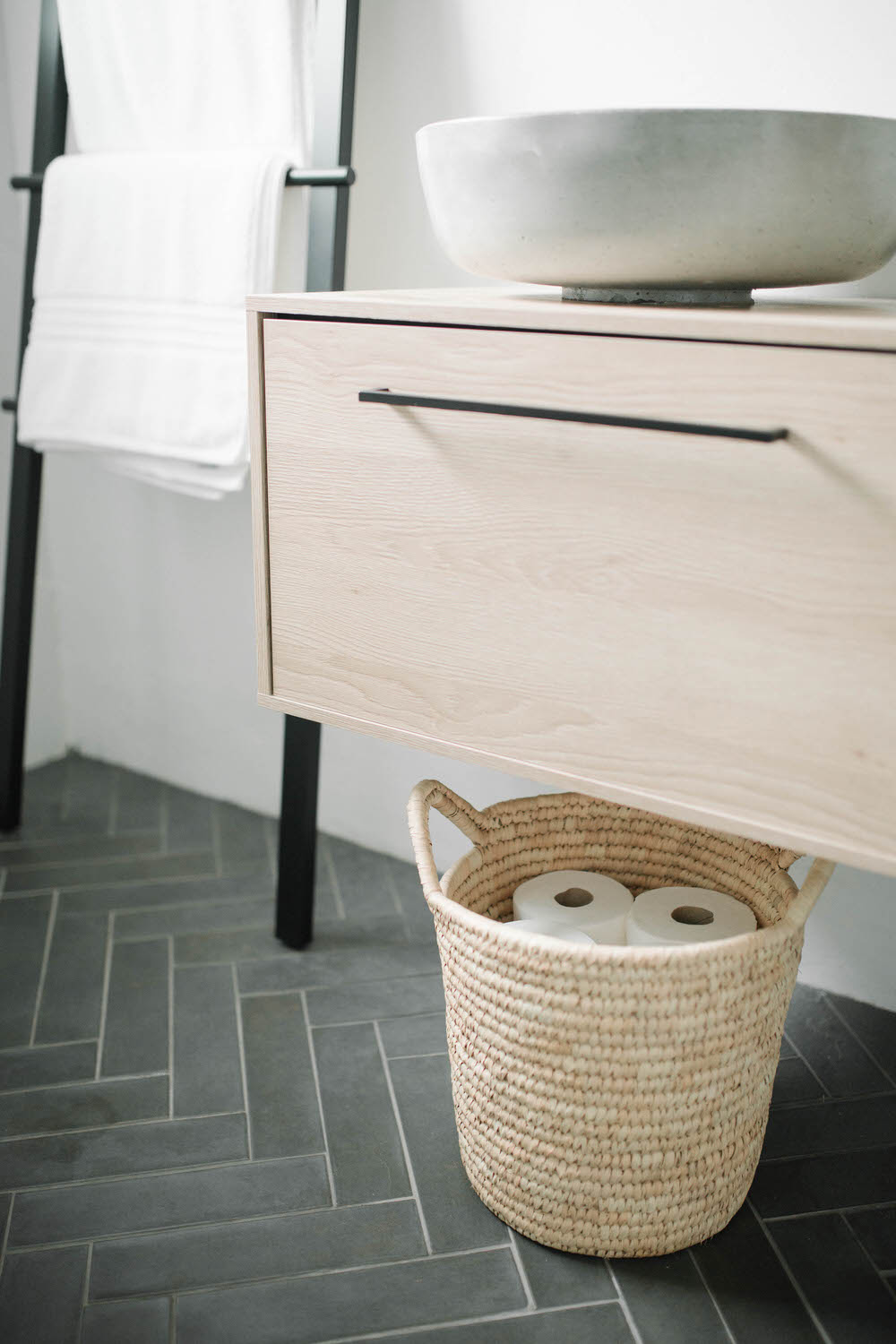 Basket of toilet rolls in scandi style bathroom