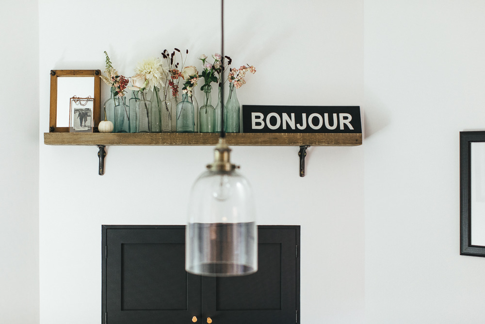 Bonjour sign by Sign Hive with vintage bottles and dark cupboard