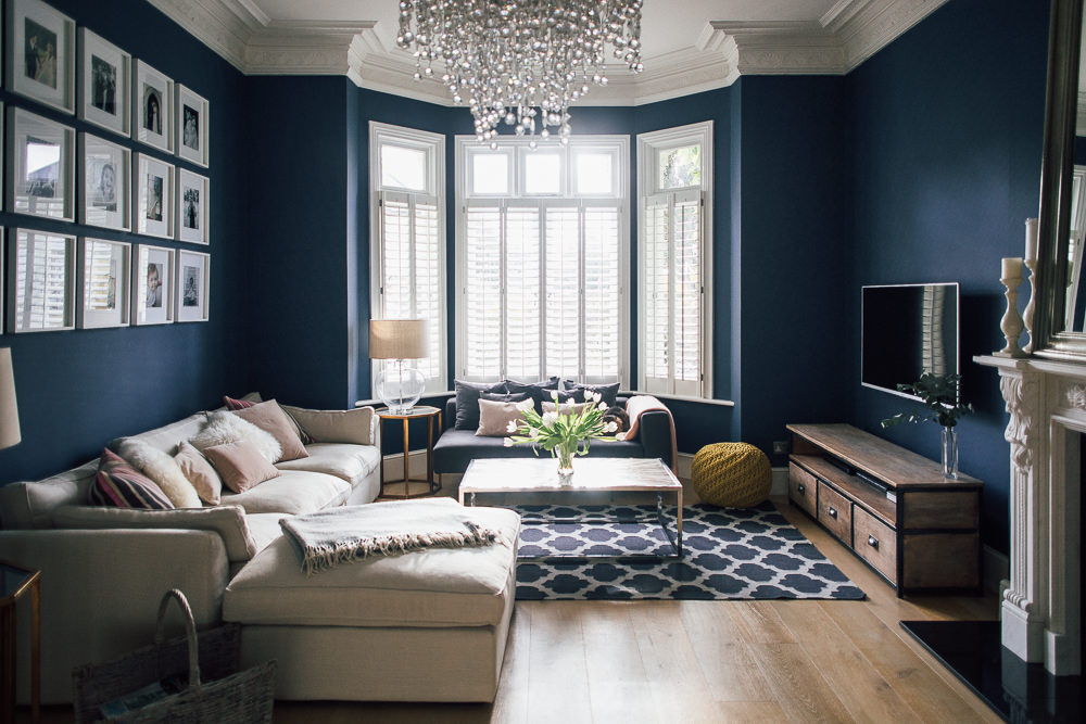 Dark blue sitting room with shutters and glass chandelier