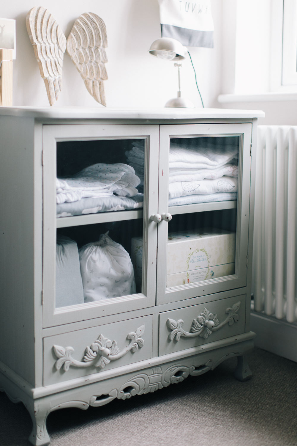 Vintage style linen cupboard with muslins and sleep sacks in nursery