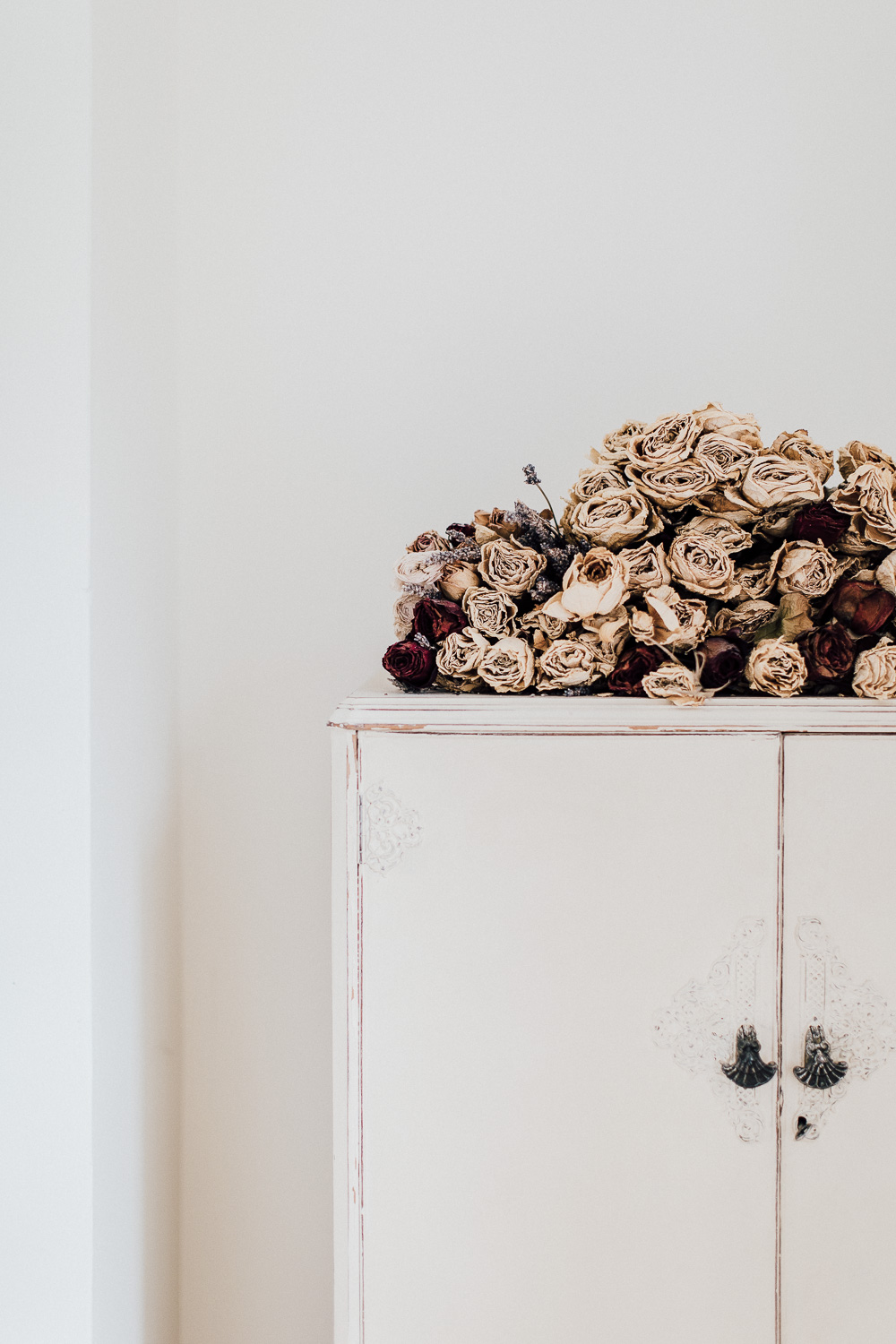 Dried roses on vintage painted distressed cupboard