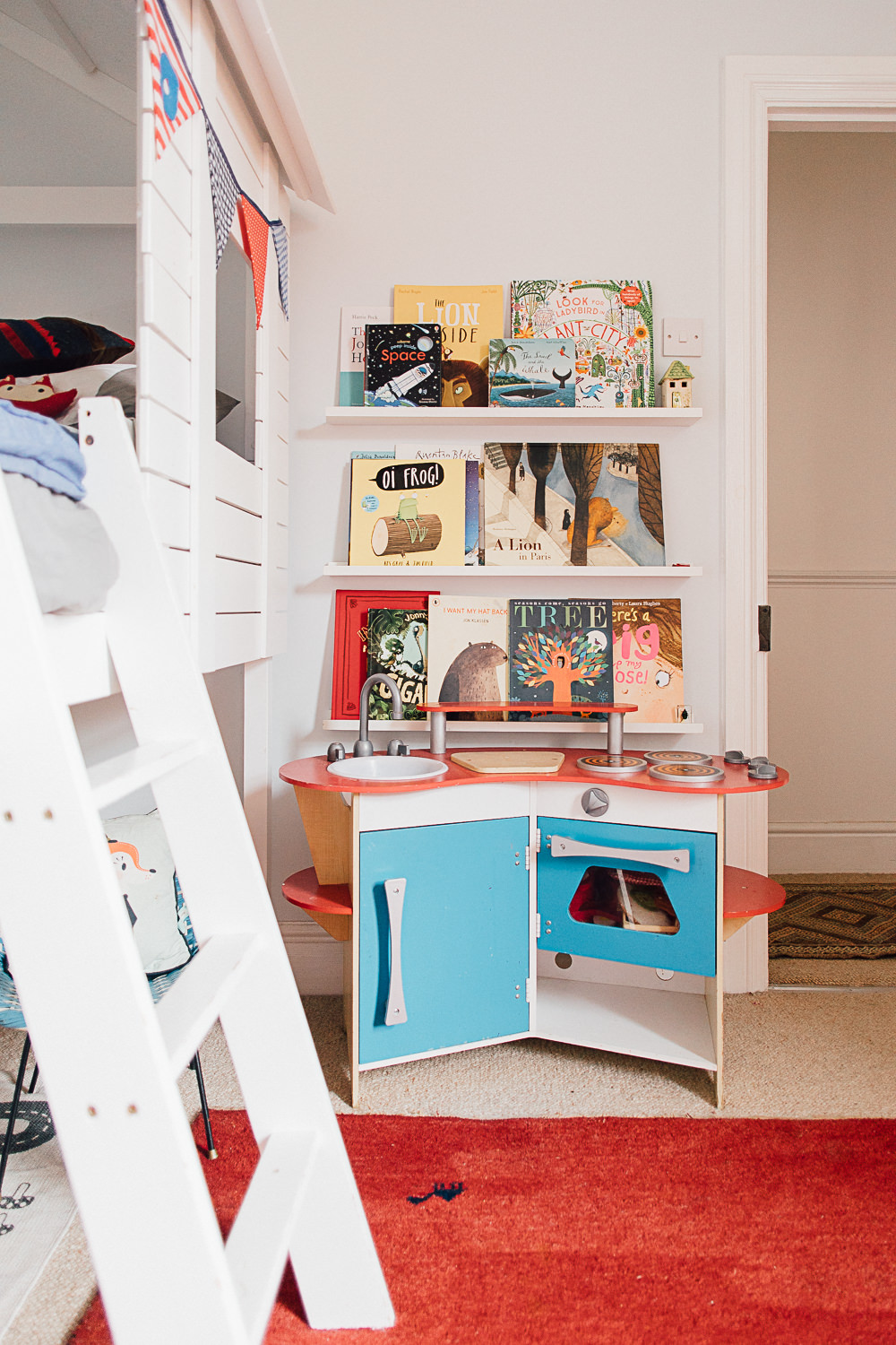 Toy kitchen beneath a colourful book wall