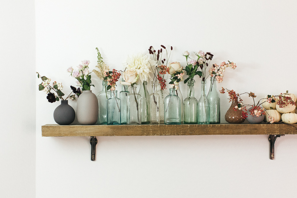 Shelf with autumn flowers and white pumpkins